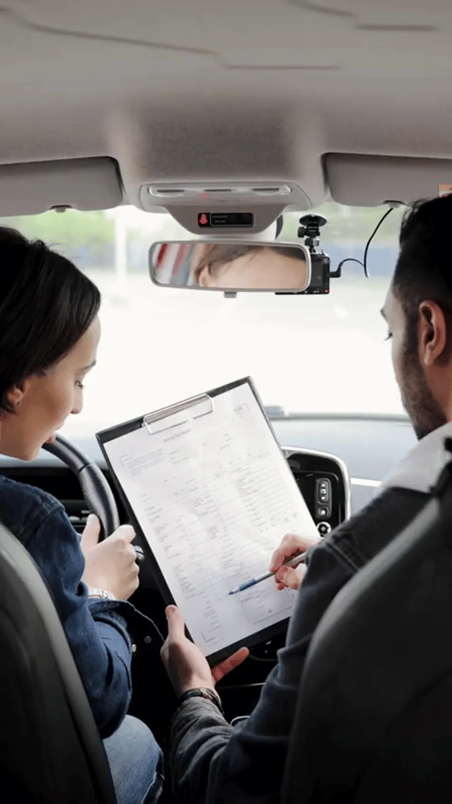 A driving instructor reviewing a road-test sheet with a student